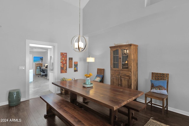 dining area with dark hardwood / wood-style flooring, a chandelier, and high vaulted ceiling