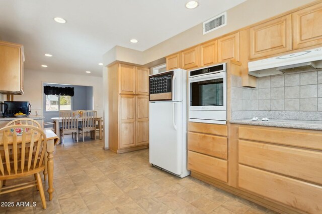 kitchen featuring light brown cabinets, white appliances, and tasteful backsplash