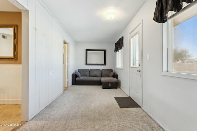 corridor featuring wood walls, a healthy amount of sunlight, and light colored carpet