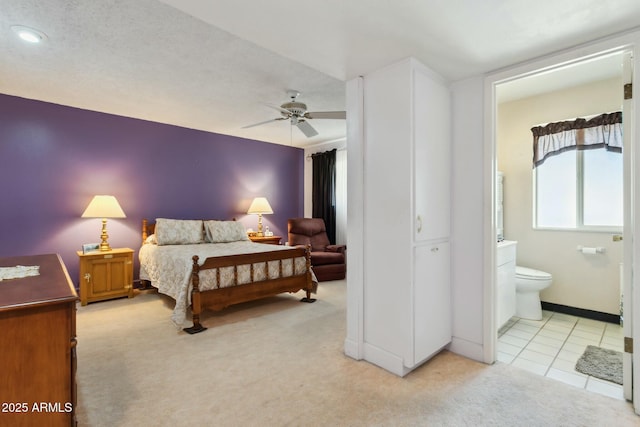 bedroom featuring light tile patterned floors, ensuite bathroom, and ceiling fan