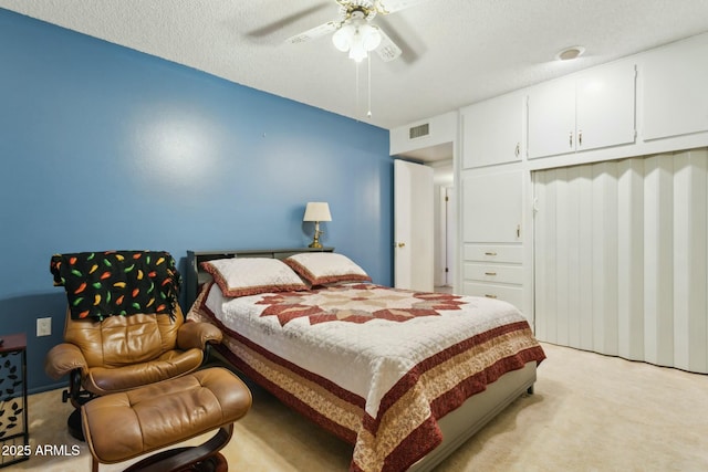 bedroom featuring ceiling fan, light colored carpet, and a textured ceiling