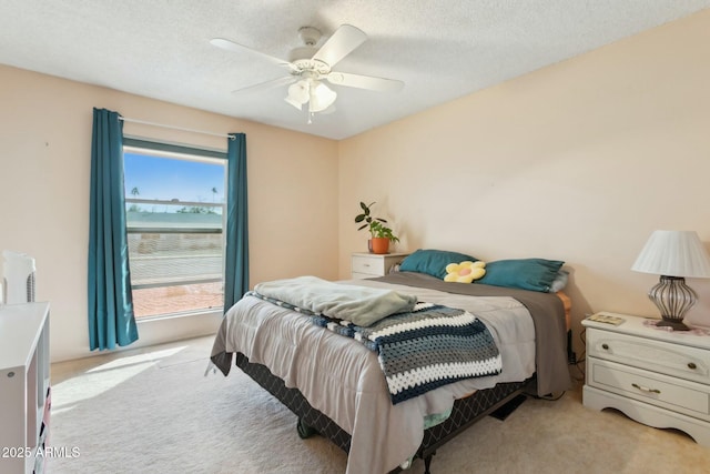 carpeted bedroom featuring ceiling fan and a textured ceiling