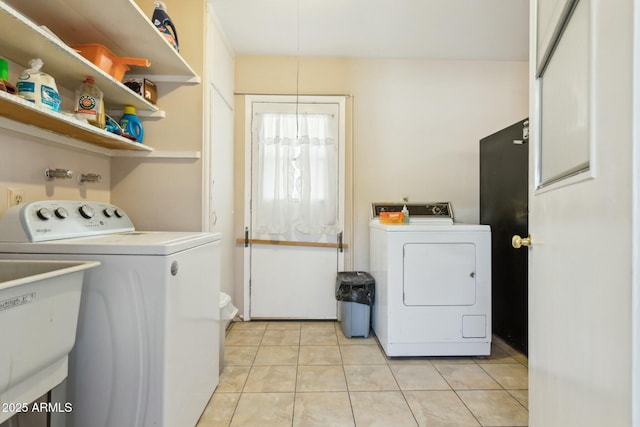 laundry area with light tile patterned floors, washing machine and dryer, and sink