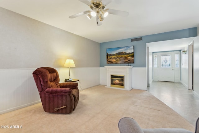 sitting room with ceiling fan and light colored carpet