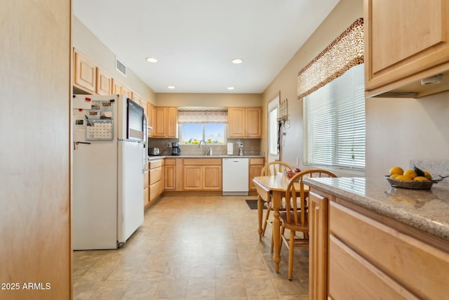 kitchen with light stone countertops, light brown cabinetry, decorative backsplash, white appliances, and sink