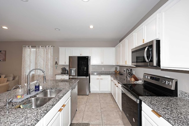 kitchen featuring appliances with stainless steel finishes, white cabinetry, sink, and dark stone counters