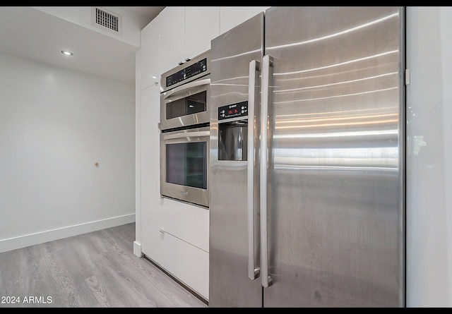 kitchen with white cabinets, light hardwood / wood-style floors, and appliances with stainless steel finishes