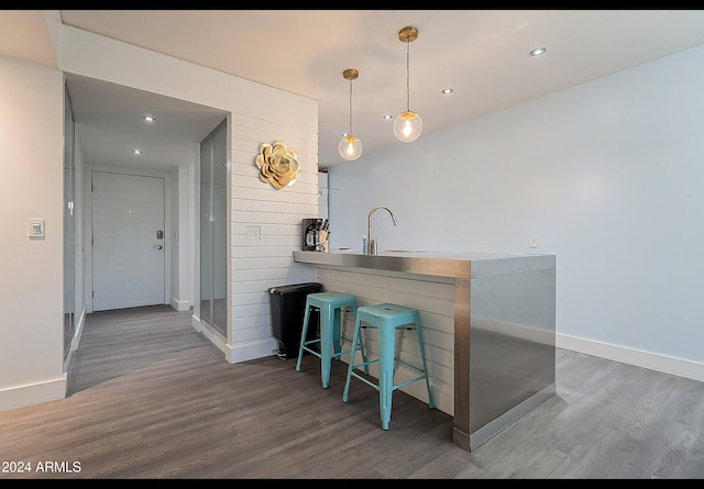 bar featuring hanging light fixtures, dark wood-type flooring, and sink