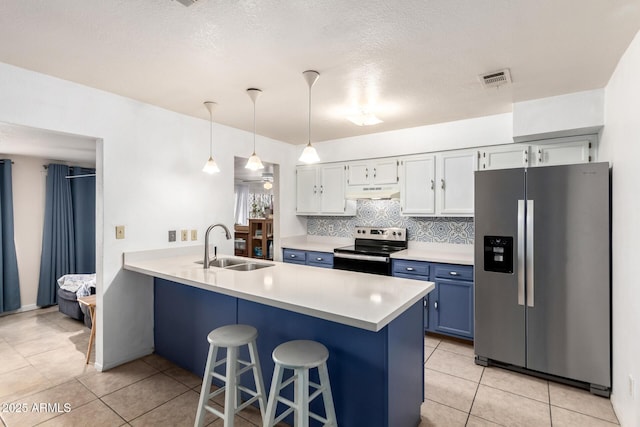 kitchen with a breakfast bar, a sink, under cabinet range hood, appliances with stainless steel finishes, and a peninsula