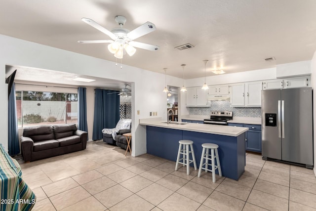 kitchen with a breakfast bar area, visible vents, a peninsula, under cabinet range hood, and appliances with stainless steel finishes