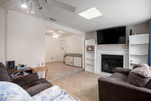 living area featuring light tile patterned flooring, visible vents, a fireplace, and a ceiling fan