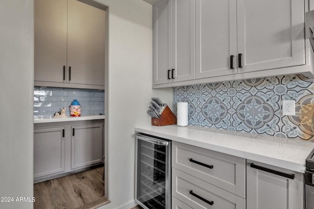 kitchen featuring backsplash, light stone counters, light hardwood / wood-style flooring, and beverage cooler