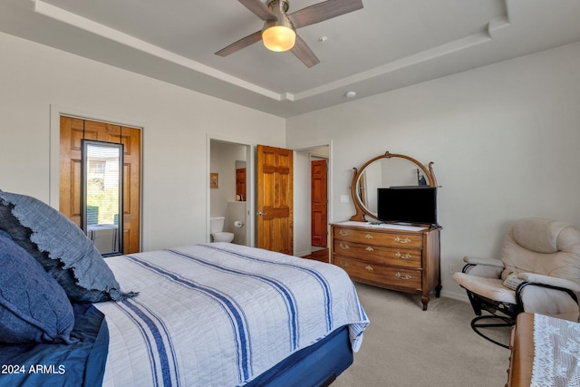 carpeted bedroom featuring ensuite bath, a raised ceiling, and ceiling fan