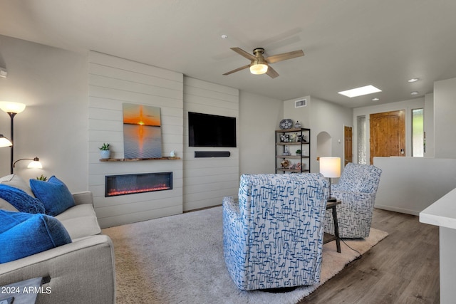 living room featuring a large fireplace, wood-type flooring, and ceiling fan