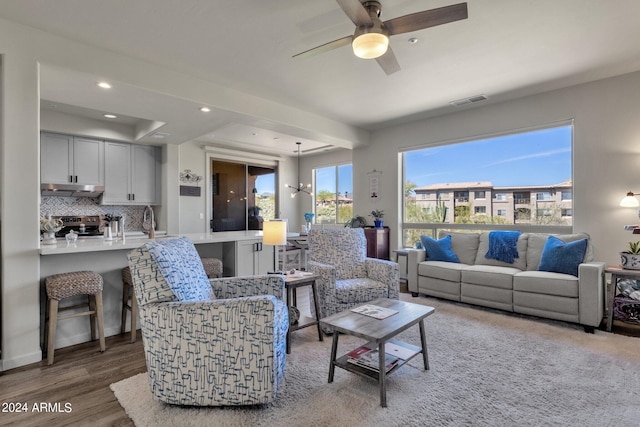 living room with wood-type flooring, ceiling fan, and sink