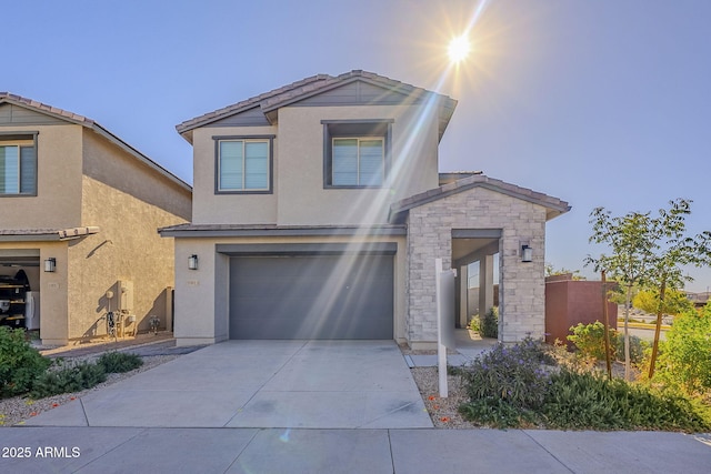 view of front of house with stucco siding, driveway, a tile roof, stone siding, and an attached garage