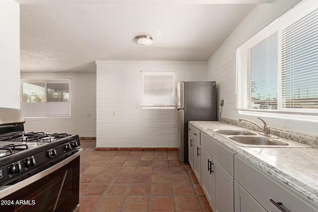 kitchen featuring gas stove, stainless steel refrigerator, a wealth of natural light, and sink