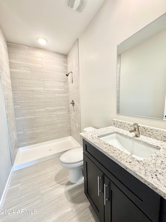 bathroom with vanity, a tile shower, and toilet