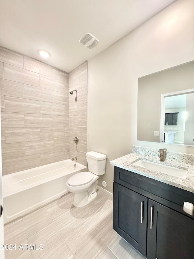 full bathroom with tiled shower / bath, vanity, and toilet