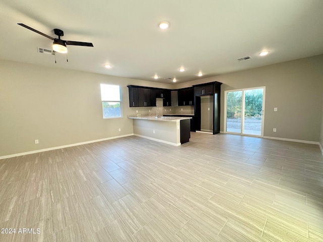 kitchen with light stone counters, ceiling fan, wood-type flooring, and plenty of natural light