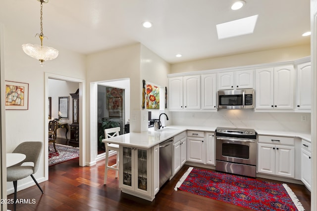 7955 E Chaparral Rd Unit 129, Scottsdale, AZ 85250 - kitchen featuring appliances with stainless steel finishes, a skylight, dark wood finished floors, white cabinets, and light countertops