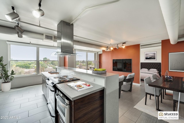 kitchen with visible vents, light countertops, electric range, track lighting, and island range hood