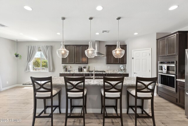 2741 S Gordon, Mesa, AZ 85209 - kitchen with wall chimney range hood, a kitchen island with sink, light wood-style floors, dark brown cabinetry, and recessed lighting