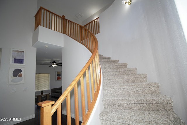 stairs featuring a towering ceiling and ceiling fan