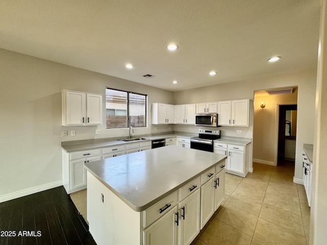 kitchen featuring stainless steel appliances, a kitchen island, sink, and white cabinets