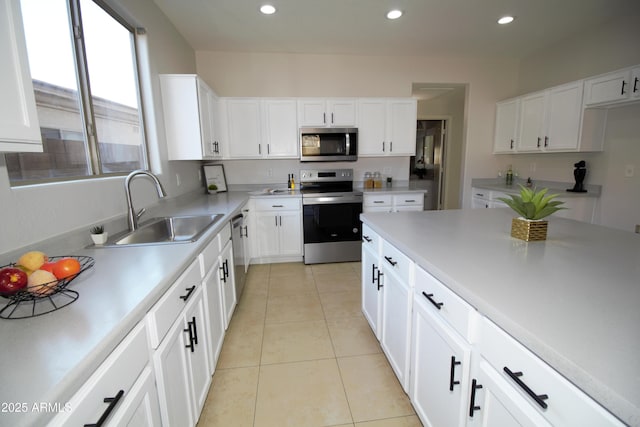 kitchen featuring white cabinetry, sink, light tile patterned floors, and appliances with stainless steel finishes