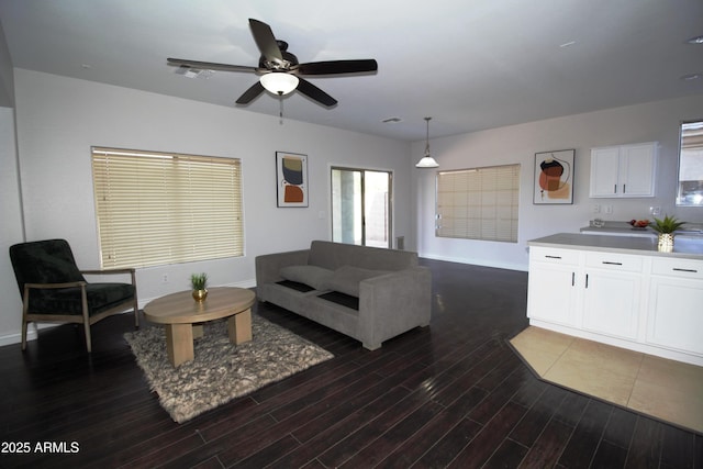 living room featuring dark wood-type flooring and ceiling fan