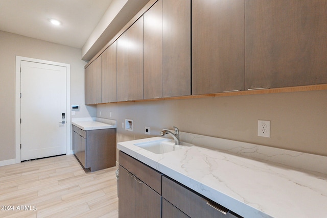 laundry area featuring sink, cabinets, hookup for a washing machine, hookup for an electric dryer, and light hardwood / wood-style flooring