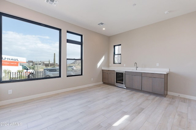 bar with wine cooler, sink, and light hardwood / wood-style floors