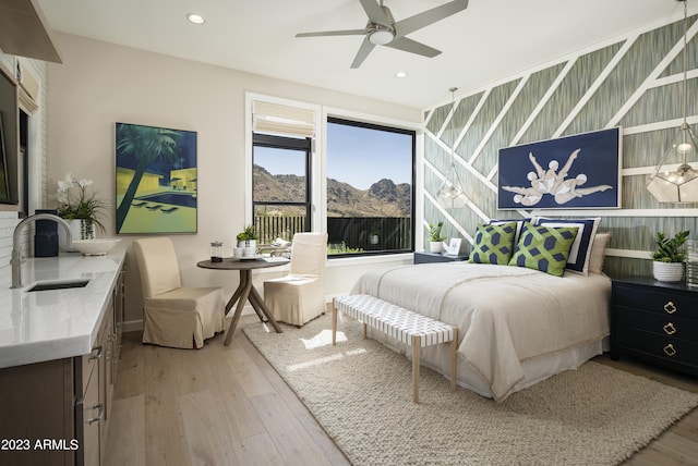 bedroom with a mountain view, sink, ceiling fan, and light hardwood / wood-style floors