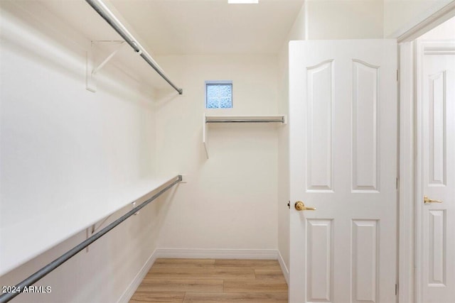 walk in closet with light hardwood / wood-style flooring