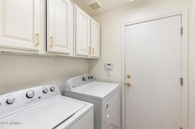 laundry room featuring washing machine and clothes dryer and cabinets