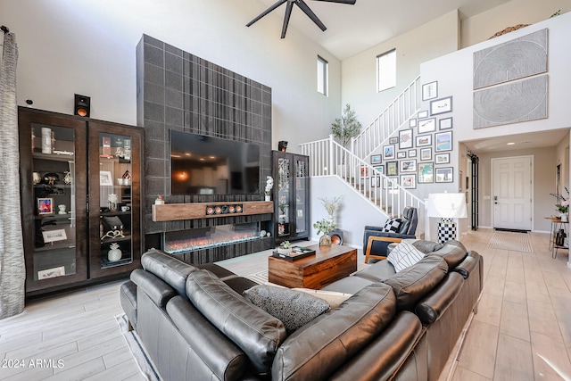 living room featuring ceiling fan, a high ceiling, and light wood-type flooring