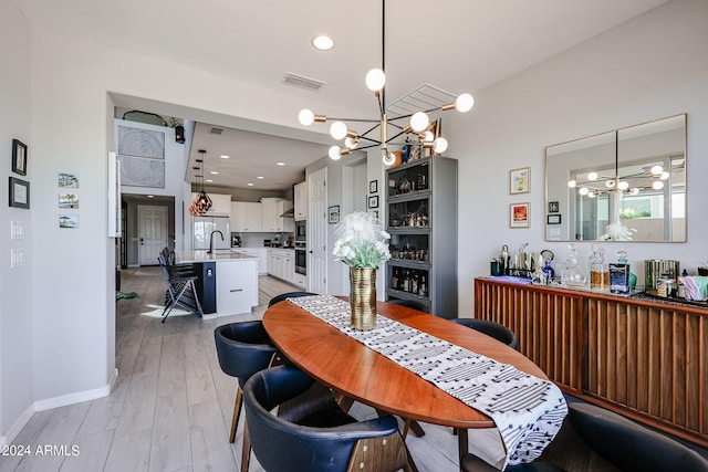 dining area with a notable chandelier, sink, and light wood-type flooring