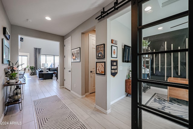 hall featuring a barn door and light hardwood / wood-style floors