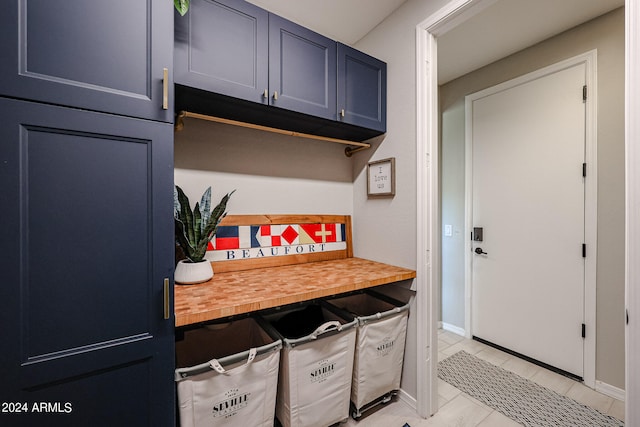 kitchen featuring wood counters, blue cabinets, and light tile patterned floors