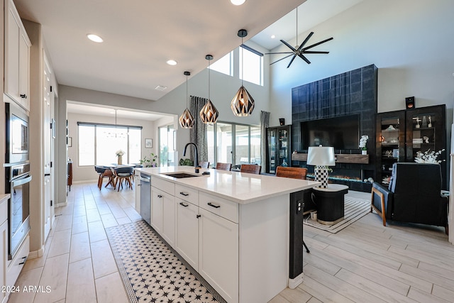 kitchen with sink, white cabinetry, a towering ceiling, and an island with sink