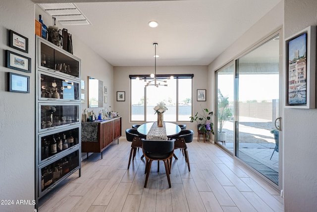 dining area with light hardwood / wood-style floors and an inviting chandelier