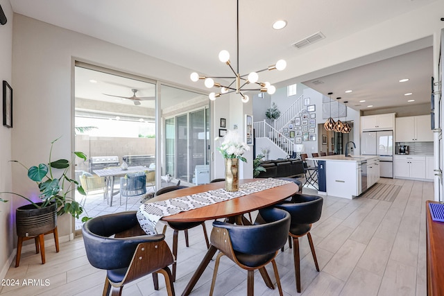 dining room with sink, light hardwood / wood-style flooring, and ceiling fan with notable chandelier