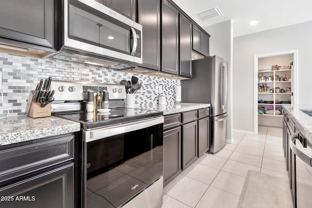 kitchen with light stone counters, light tile patterned flooring, visible vents, appliances with stainless steel finishes, and tasteful backsplash