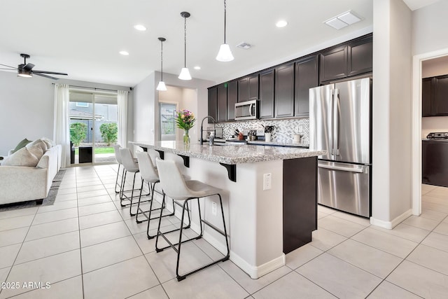 kitchen with open floor plan, stainless steel appliances, light tile patterned floors, and backsplash