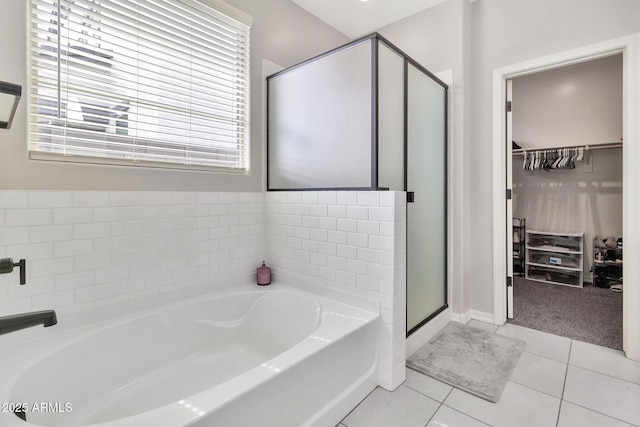 full bath with a garden tub, a shower stall, a spacious closet, and tile patterned floors