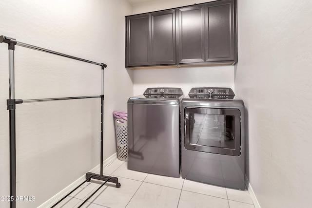 clothes washing area with light tile patterned floors, independent washer and dryer, cabinet space, and baseboards