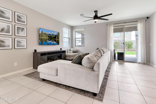 living area featuring light tile patterned flooring, ceiling fan, visible vents, and baseboards