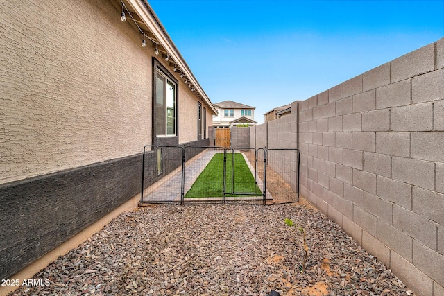 view of yard with a fenced backyard and a gate