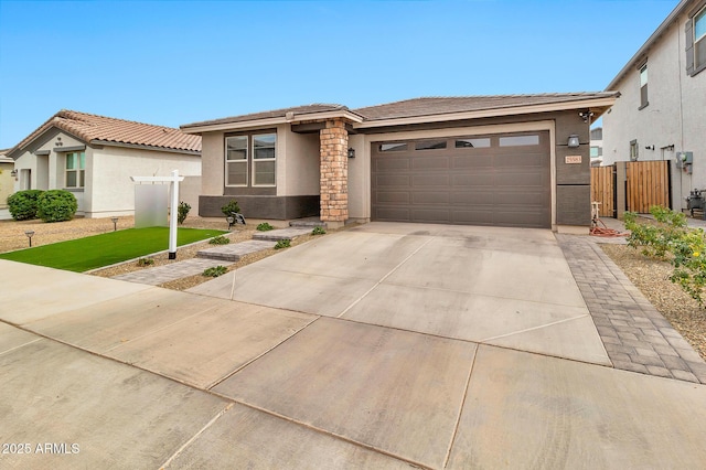 prairie-style home featuring concrete driveway, a tile roof, an attached garage, fence, and stucco siding